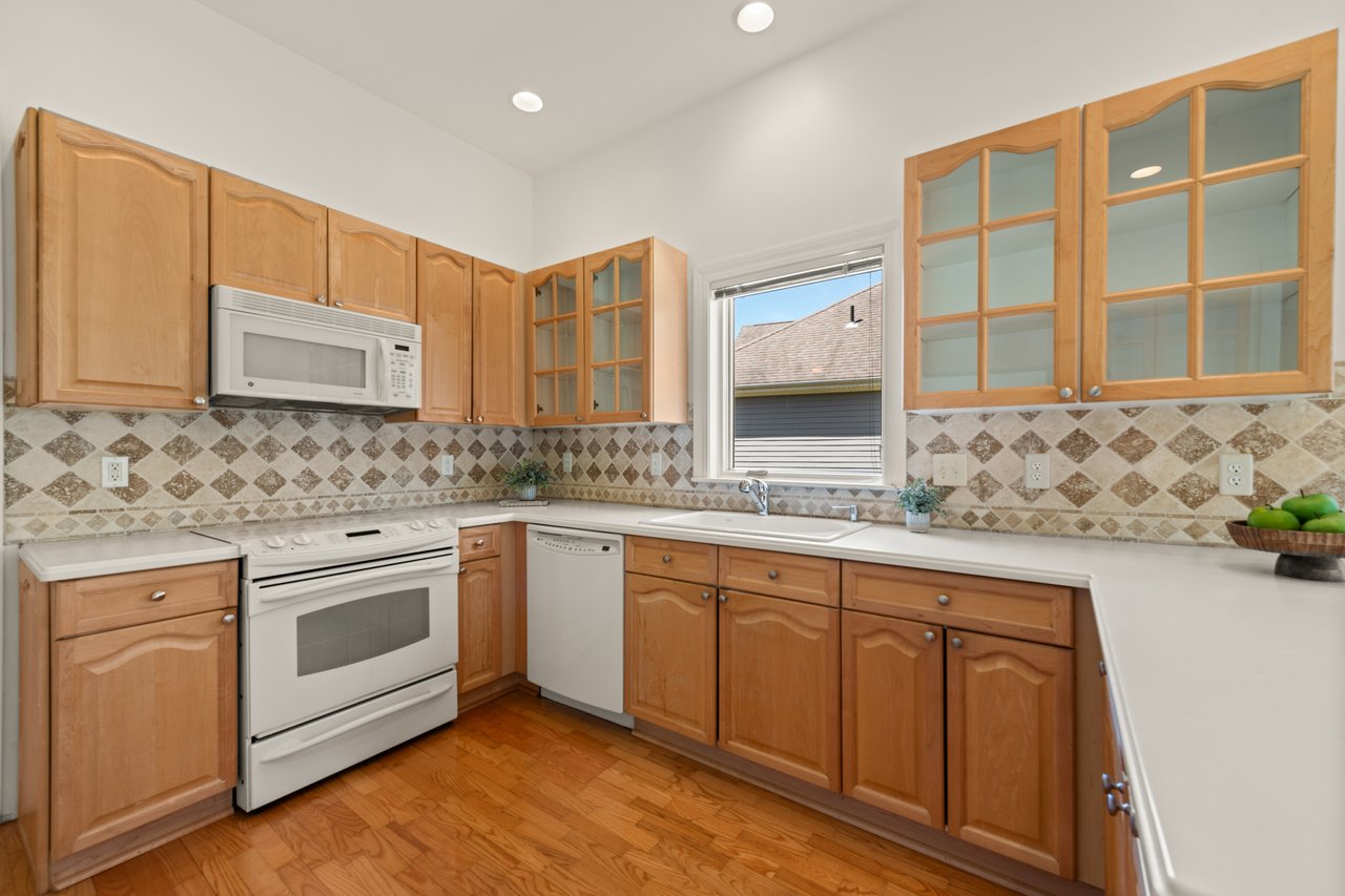 Maple cabinetry and Corian countertops with decorative, custom tile backsplash