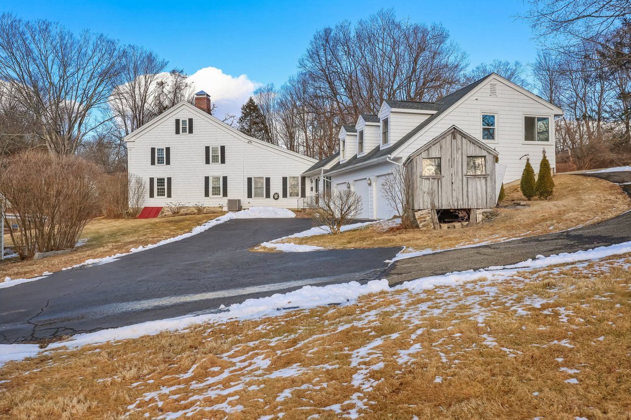 The main house, garages, and outbuildings sit nicely on the land. Classic architecture is evident, including the gabled roof lines.