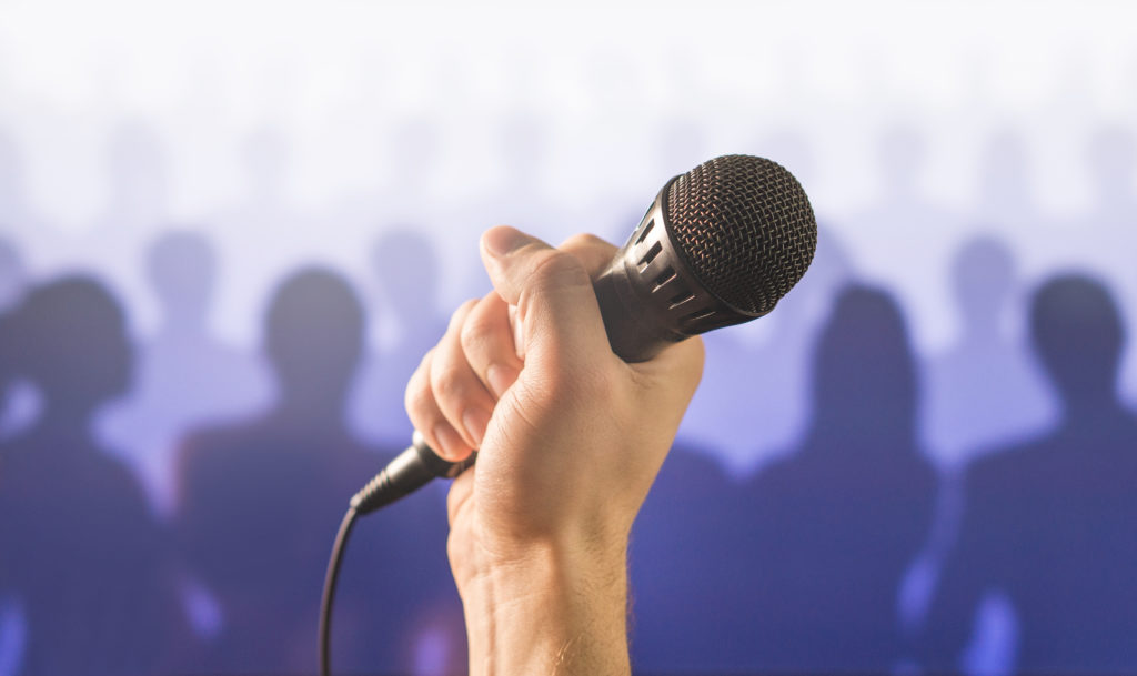 Public speaking and giving speech concept. Hand holding microphone in